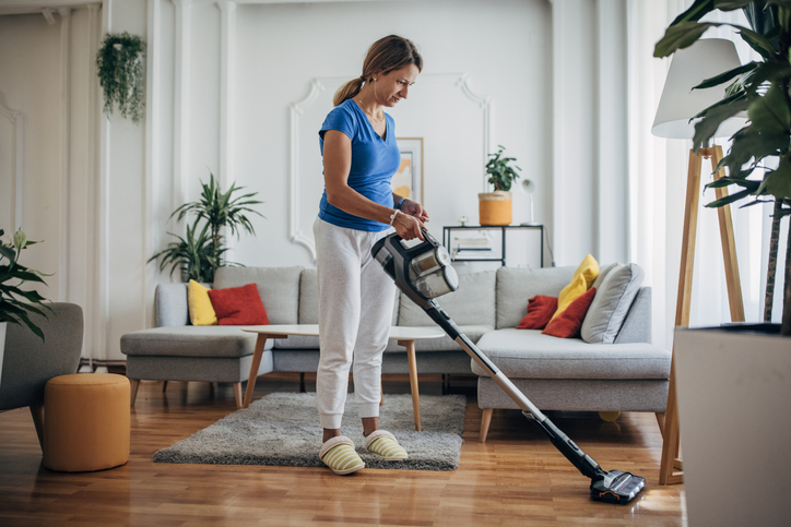 Frau saugt Teppich in einem modernen Wohnzimmer