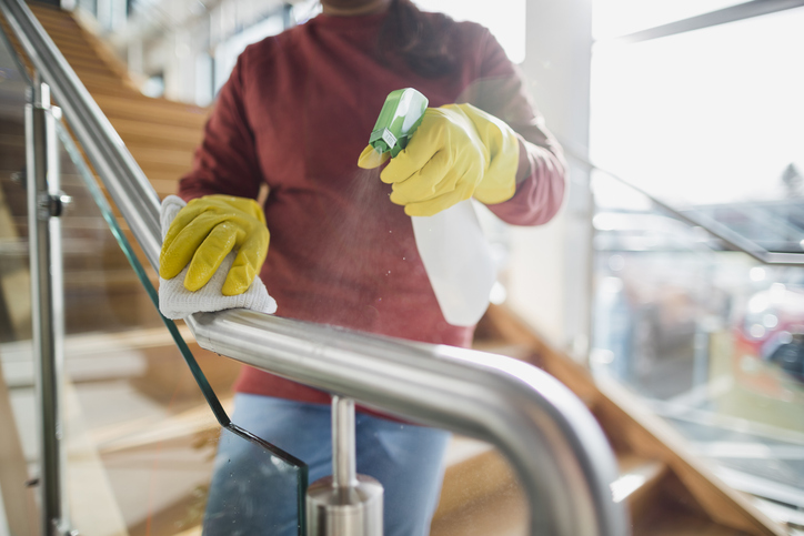 Reinigung eines Treppenhaus-Geländers mit umweltfreundlichem Reinigungsmittel durch eine professionelle Reinigungskraft.