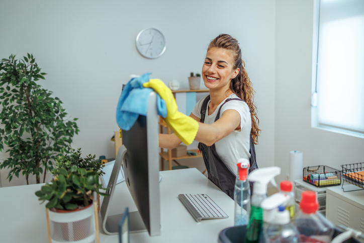 Reinigungsfachkraft bei der professionellen Büroreinigung in Freising: Monitorreinigung und hygienische Pflege des Arbeitsplatzes.